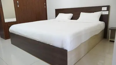 a bedroom with a large bed with white sheets at DEJAVU TRANZS - Trishul in Coimbatore