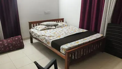 a bedroom with a wooden bed with a bedskirts at Johnnys Destination in Angamali