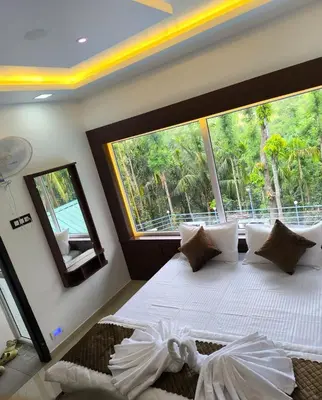a bedroom with a large bed with a large window at wild casa in Kanthalloor