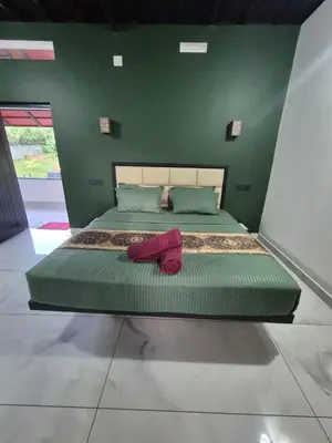 a bedroom with a large bed with green walls at Cabana banasura Wayanad 2bhk in Padinjarathara