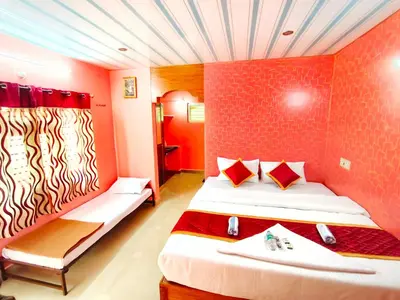 a room with a bed and a red wall at Rising Surya Homestay in Kushālnagar