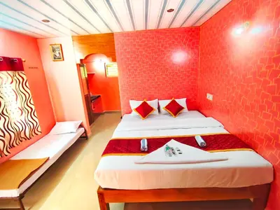 a room with two beds and a red wall at Rising Surya Homestay in Kushālnagar