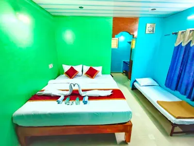 a bedroom with two beds with green walls at Rising Surya Homestay in Kushālnagar