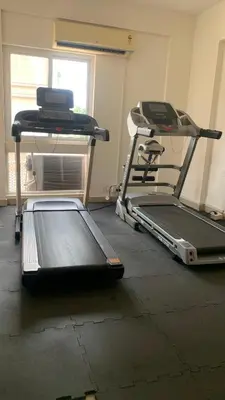 a room with a treadmill and a laptop on a table at Aarav Stays in Mysore