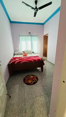 a bedroom with a bed with a red comforter at Mysore Stopover in Mysore