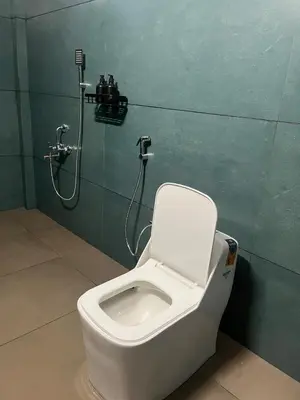 a bathroom with a white toilet in a green wall at Farmscape Retreat in Gonikoppal