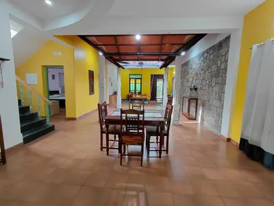 a dining room with a table and chairs and yellow walls at SHI's Chettinad Courtyard Villa a 3BHK near Adiyogi in Alāndurai