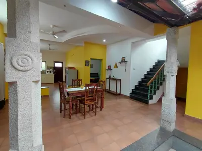 a living room with a table and chairs and a staircase at SHI's Chettinad Courtyard Villa a 3BHK near Adiyogi in Alāndurai