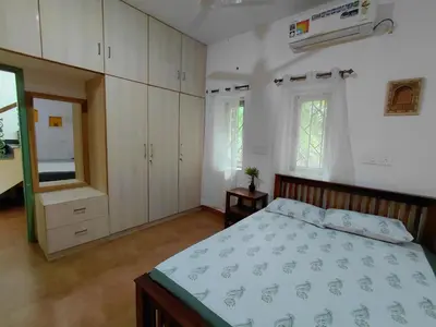 a bedroom with a bed and white cabinets and a window at SHI's Chettinad Courtyard Villa a 3BHK near Adiyogi in Alāndurai
