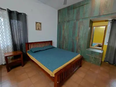 a bedroom with a bed with a wooden frame and a window at SHI's Chettinad Courtyard Villa a 3BHK near Adiyogi in Alāndurai