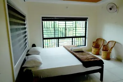 a bedroom with a bed and a large window at Daya Village in Tirūrangādi
