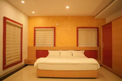 a bedroom with a large bed with two windows at The Glen By Bloobuck in Ambalavayal
