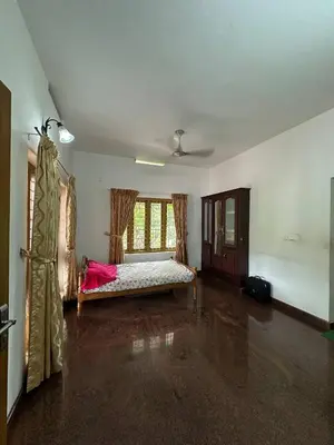 an empty room with a bed and a window at Villa Tharavadu in Angamali