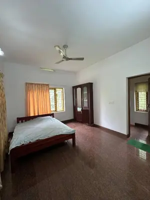 a bedroom with a bed and a ceiling fan at Villa Tharavadu in Angamali