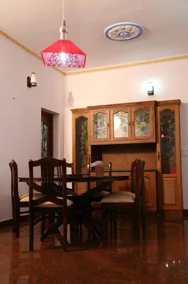 a dining room with a table and chairs and a chandelier at Villa Tharavadu in Angamali