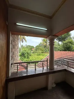 a room with a balcony with a view of a yard at Villa Tharavadu in Angamali