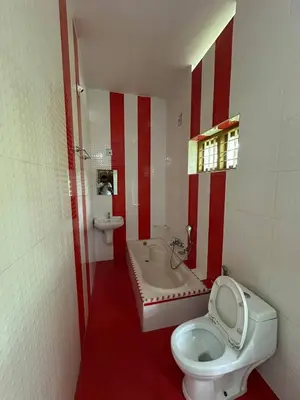 a red and white bathroom with a toilet and a tub at Villa Tharavadu in Angamali