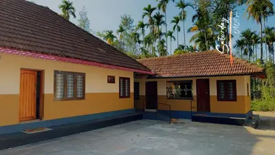 a small yellow house with a brown roof at Festoon Villa in Sultan Bathery