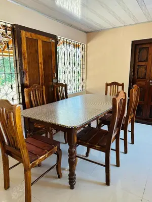 a dining room table with wooden chairs and a table and a table and chairsktop at Festoon Villa in Sultan Bathery