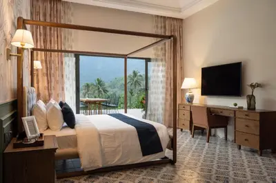 a hotel room with a bed and a desk and a television at The Ranch Kakkadampoyil - a VKation Experience in Kakkadampoyil