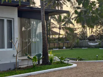 a house with a palm tree next to a yard at Reflections by SOL Escapes near Cherai Beach in Pallipuram