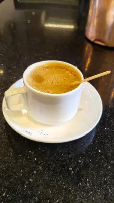 a cup of coffee on a plate on a table at South point homestay in Virajpet