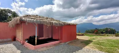 a small red building with a grass roof at Kanthalloor Mud & Mist Homestay in Kanthalloor