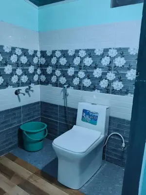 a bathroom with a toilet and a green bucket at Kanthalloor Mud & Mist Homestay in Kanthalloor