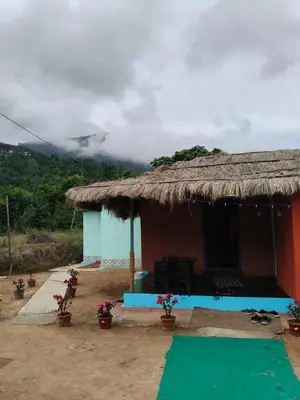 a small house with a thatched roof with flowers in front at Kanthalloor Mud & Mist Homestay in Kanthalloor