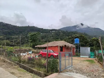 a red car parked in front of a house with a mountain at Kanthalloor Mud & Mist Homestay in Kanthalloor