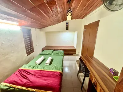 a small bedroom with a green bed and a wooden ceiling at KODIYADAN s INN A Homestay with a Heart in Meenangadi