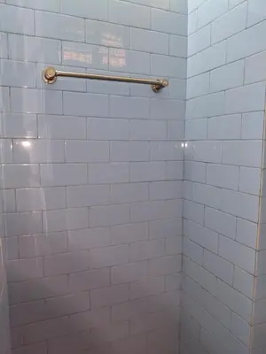 a white tiled shower with a towel rack in a bathroom at Roopa Studio in Mysore