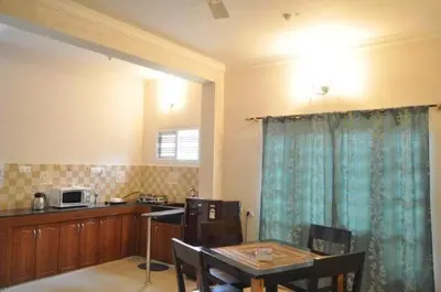 a kitchen with a dining room table and a microwave at Mulberry Bay Serviced Apartments in Mysore