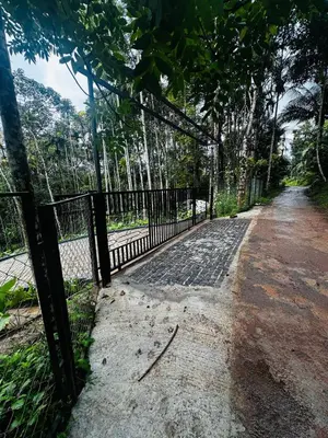 a fence next to a dirt road with trees at ThunderHill by Casablanca - A Premium Pool Villa in Meenangadi