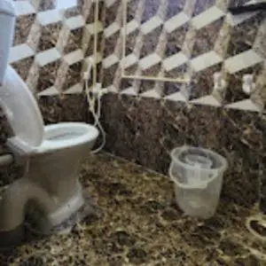 a dirty bathroom with a toilet and a bucket at Sai Home Stay in Marudhamalai