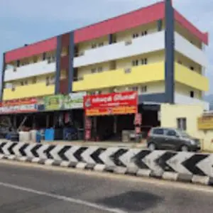 a building with a car parked in front of a street at Sai Home Stay in Marudhamalai