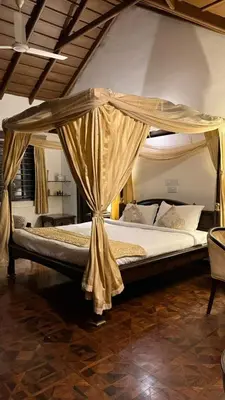 a bed with a canopy in a room at Hotel green land in Madikeri