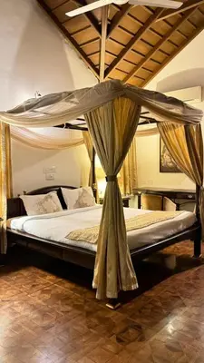 a bed with a canopy in a room at Hotel green land in Madikeri