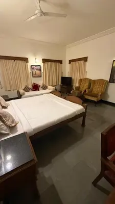 a bedroom with a large bed and a living room at Hotel green land in Madikeri