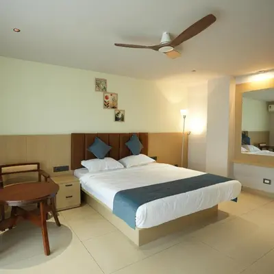 a bedroom with a bed and a table and a mirror at Nine, Boutique hotel with luxury room stay, mysore in Mysore