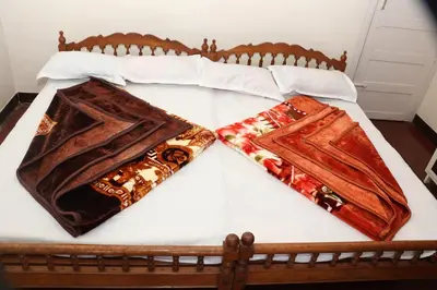 a bed with two blankets on top of it at GEE VEE Home Stay in Munnar