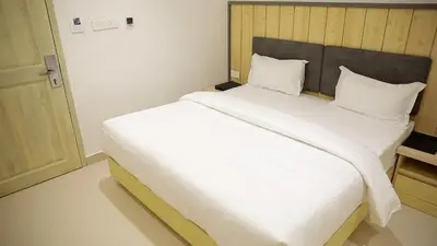 a bedroom with a large white bed with a wooden headboard at Vanaalayam Retreat Palladam By Arcadia in Palladam