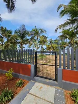 a black gate with palm trees in the background at Dream nest beach house Resort with private beach entrance in Trichūr