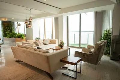 a living room with a couch and chairs and windows at MARINE DRIVE - BEACH FRONT LUXURY PENTHOUSE by NIOTEL in Kozhikode
