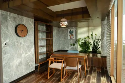 a dining room with a table and chairs and a clock at MARINE DRIVE - BEACH FRONT LUXURY PENTHOUSE by NIOTEL in Kozhikode