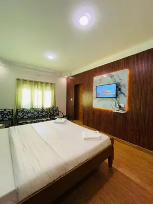 a bedroom with a bed and a tv on a wall at Coolspot Cottage in Ooty