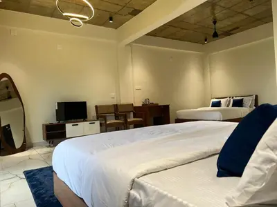a hotel room with two beds and a television at Gcc Saffron in Wayanad
