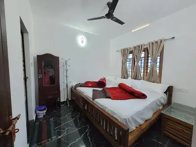 a bedroom with a bed with red pillows on it at Wildlife Homestay in Kanthalloor