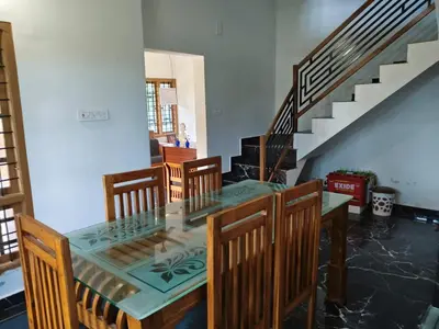 a dining room with a glass table and wooden chairs at Wildlife Homestay in Kanthalloor