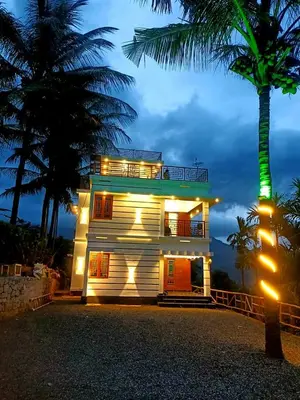 a house with a palm tree in front of it at Wildlife Homestay in Kanthalloor